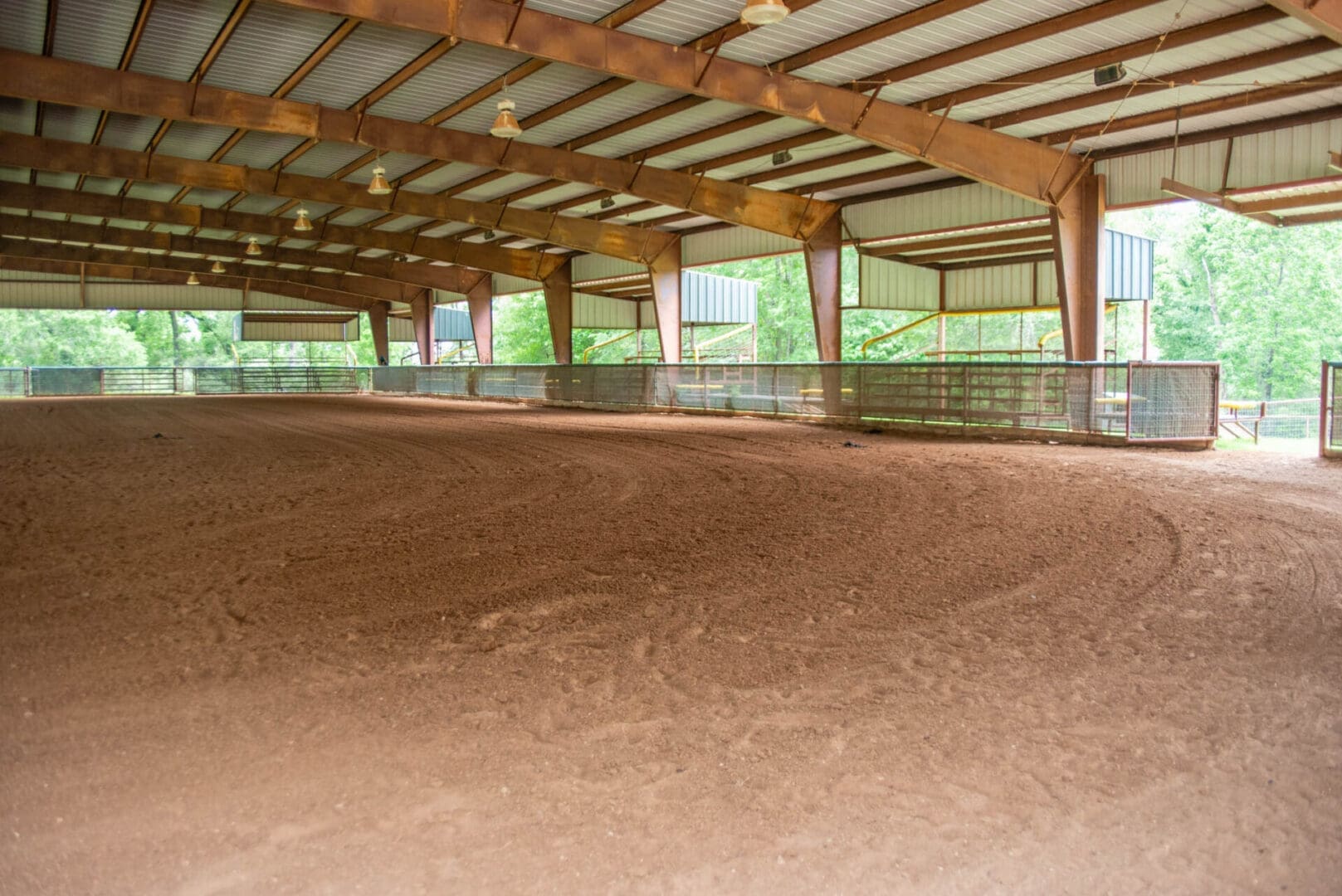 Covered dirt riding arena with metal beams