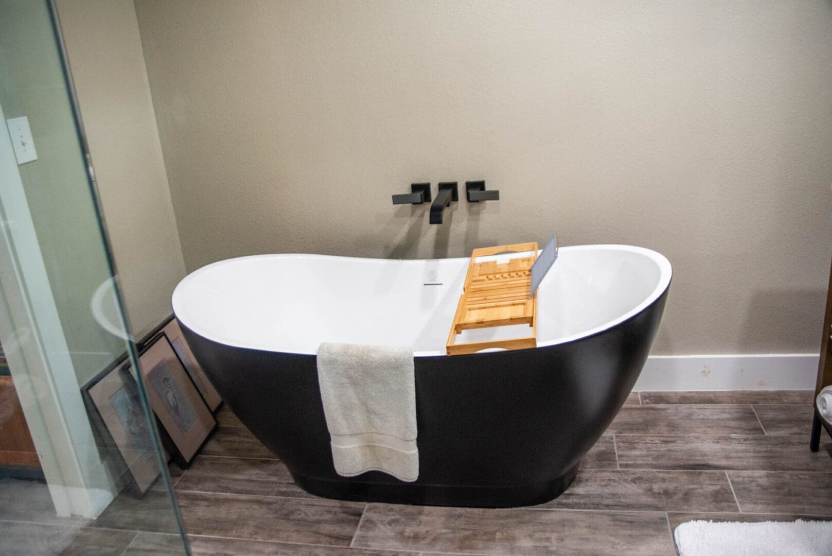 Black freestanding bathtub with towel and caddy